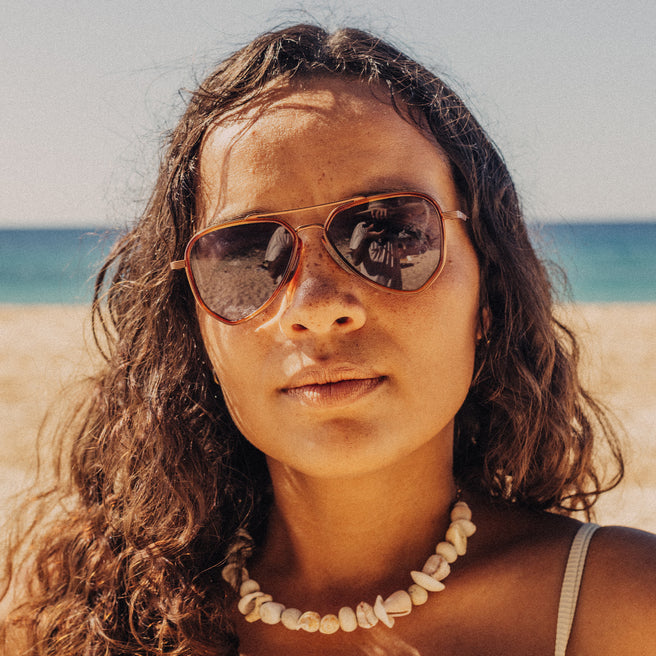 Woman wearing sunglasses with a beach and ocean in the background