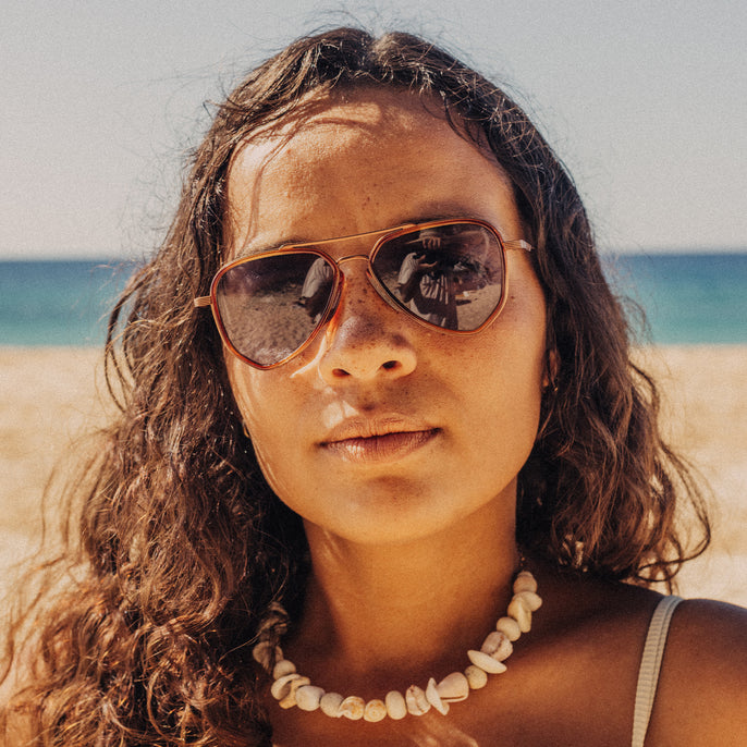 Woman wearing sunglasses with a beach and ocean in the background