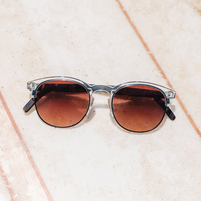Round sunglasses with brown lenses on a light textured surface