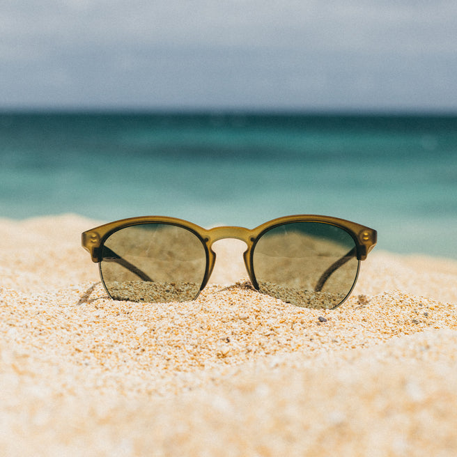 olive sunglasses in the sand at a beach