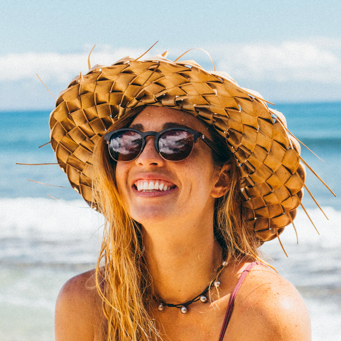 Woman wearing a straw hat and sunglasses on a beach
