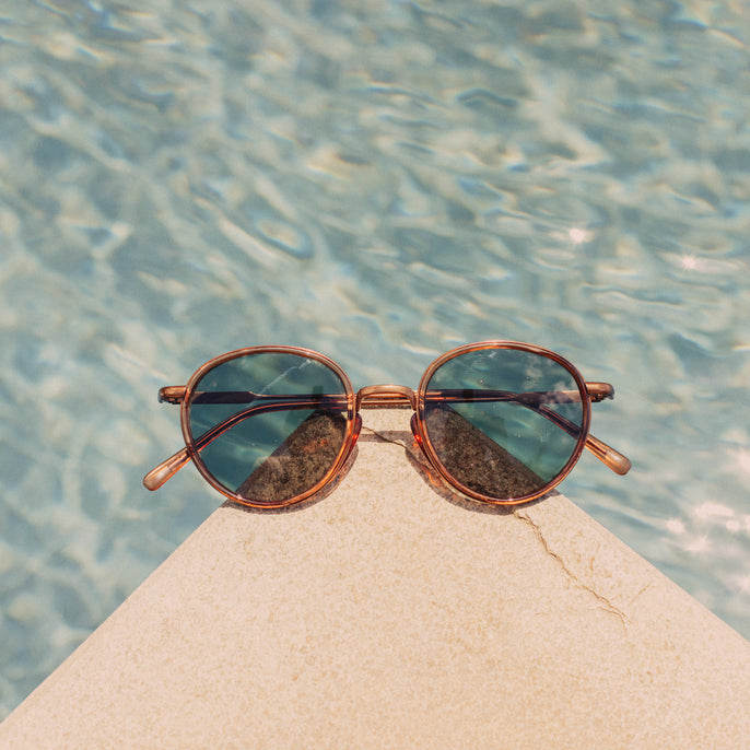 Sunglasses on a rock with water in the background