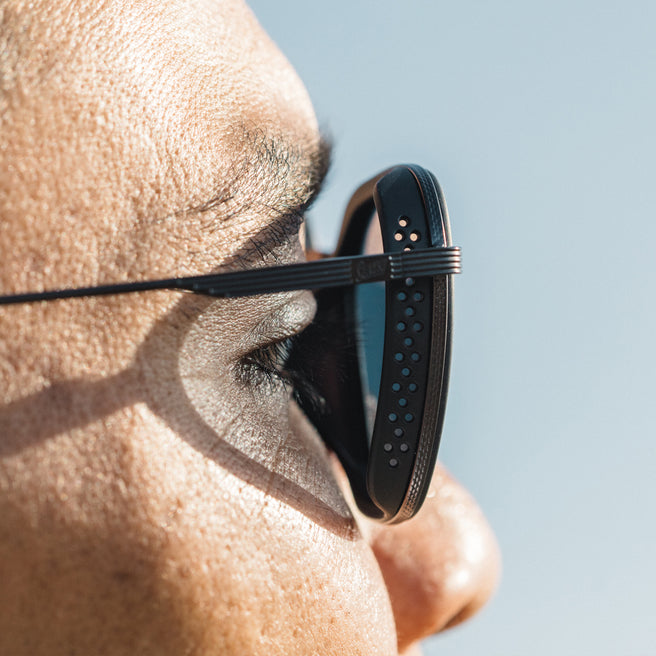 Bernina - Black Slate - Close-up of a person wearing black sunglasses with a clear blue sky background
