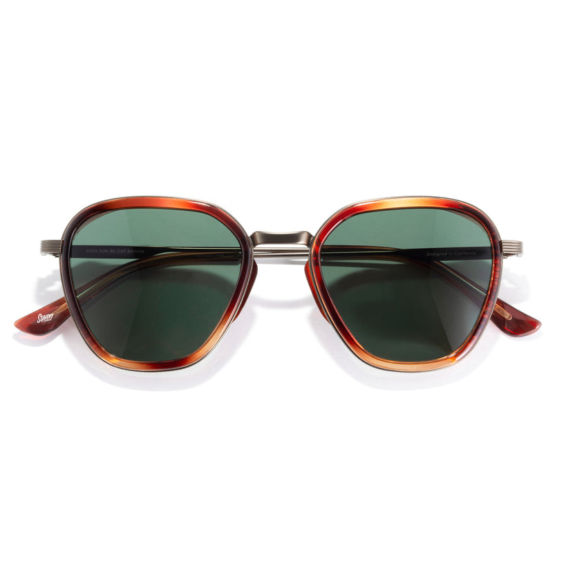 Sunglasses with tortoiseshell frame and green lenses on a white background