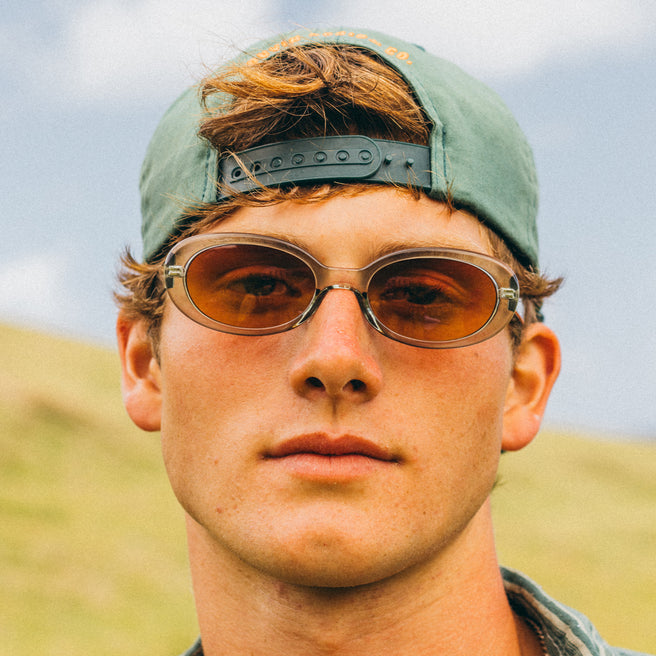 Man wearing sunglasses and a cap with a blurred natural background