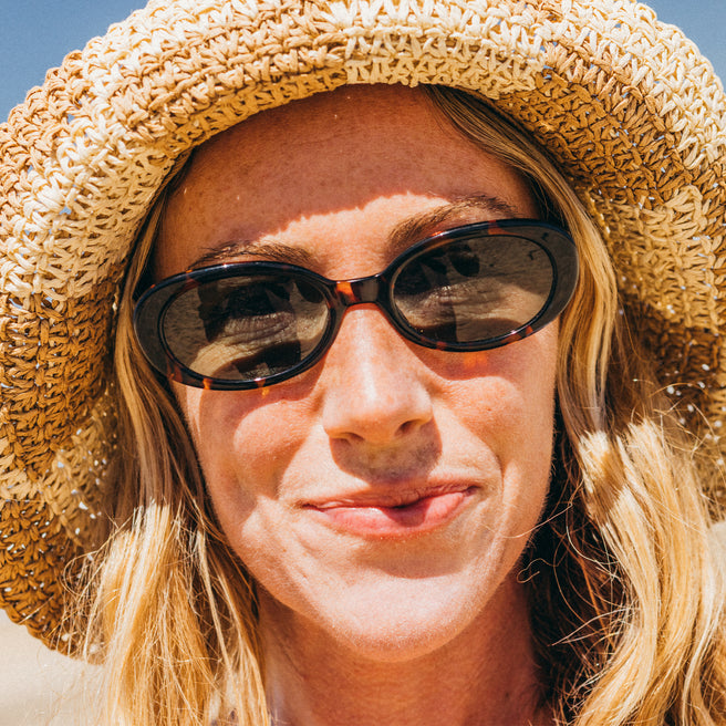 woman wearing straw hat and tortoise frame