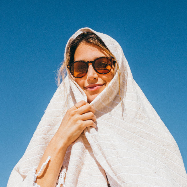 Woman wearing sunglasses and a white headscarf against a clear blue sky