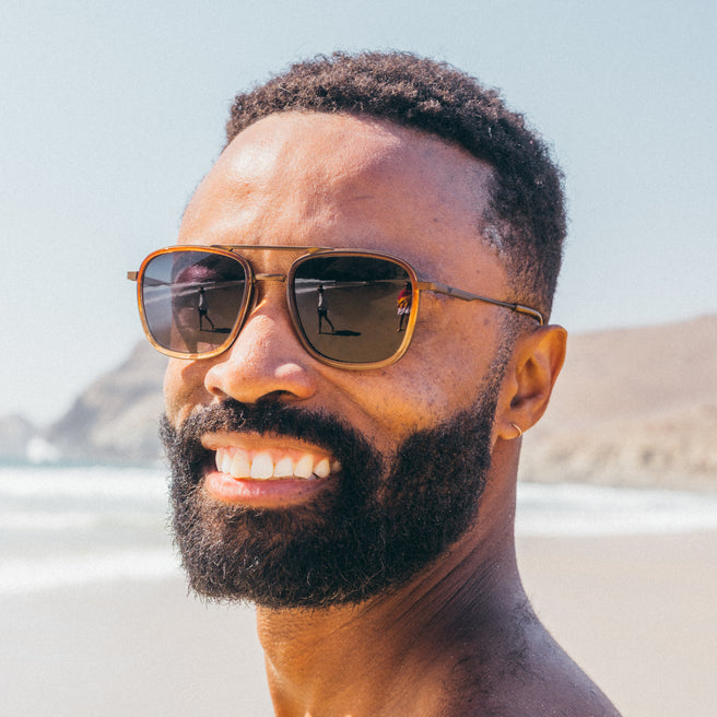 Estero - Horizon Slate - Man wearing sunglasses with a beach and mountain in the background