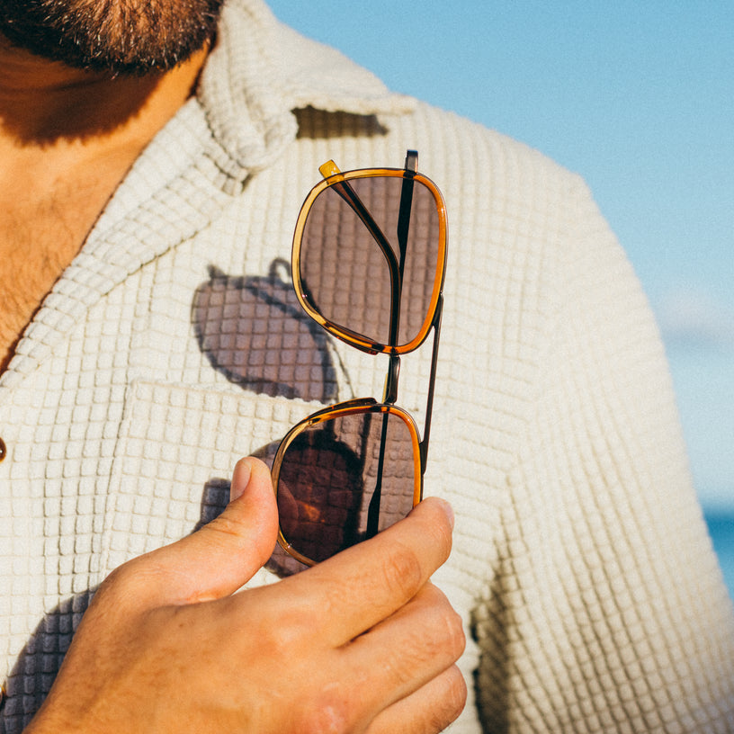 Person holding sunglasses with a blurred background