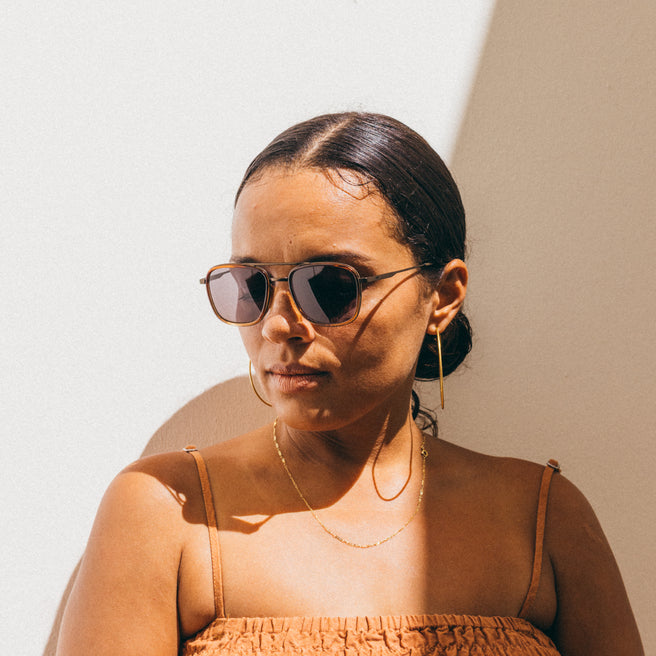 Estero - Horizon Slate - Woman wearing sunglasses and a brown top against a neutral background