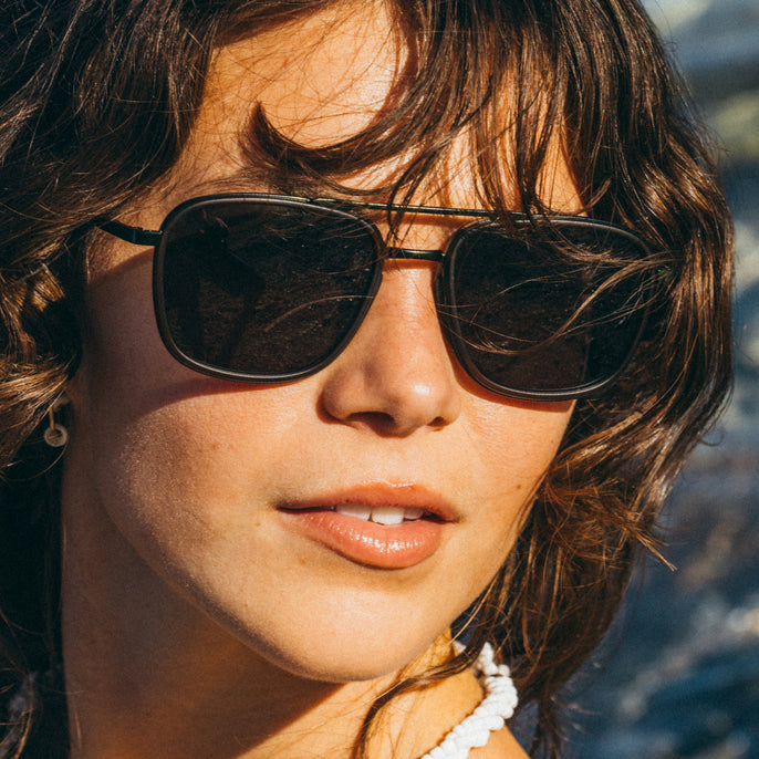 Close-up of a person wearing sunglasses with a blurred natural background