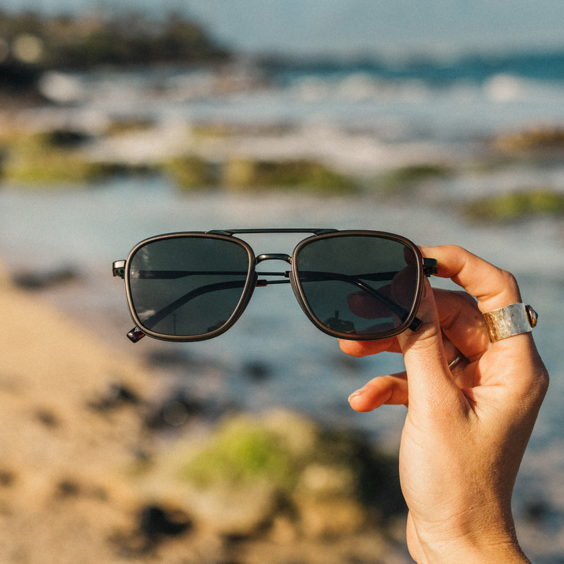 Person holding sunglasses with a blurred beach background