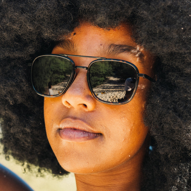 Person wearing sunglasses with a blurred natural background
