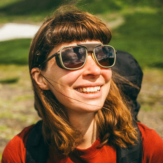 Ferrata - Olive Citrine Amber - Person wearing large sunglasses with a blurred natural background