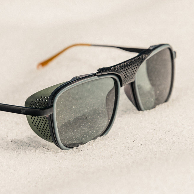 Sunglasses with black frame and gray lenses on a sandy surface