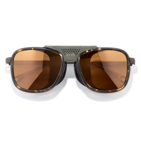 Sunglasses with brown lenses and a green frame on a white background