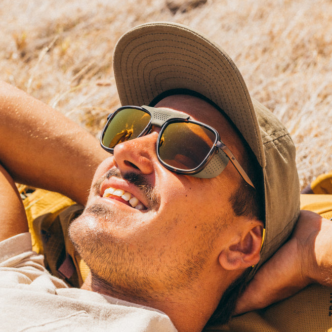 Man wearing sunglasses and a cap lying on sand