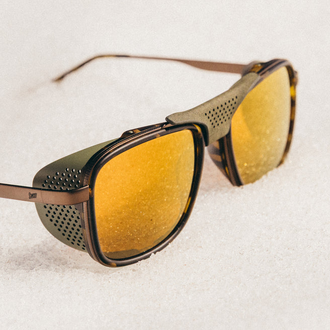 Sunglasses with gold lenses and brown frames on a white background