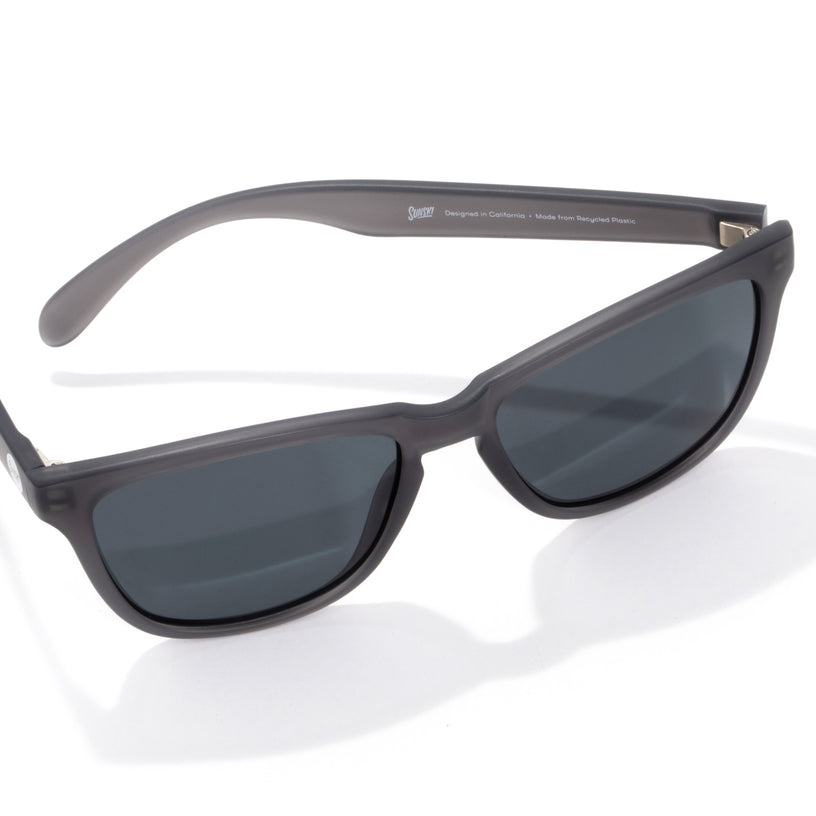 Sunglasses with dark lenses and gray frame on a white background