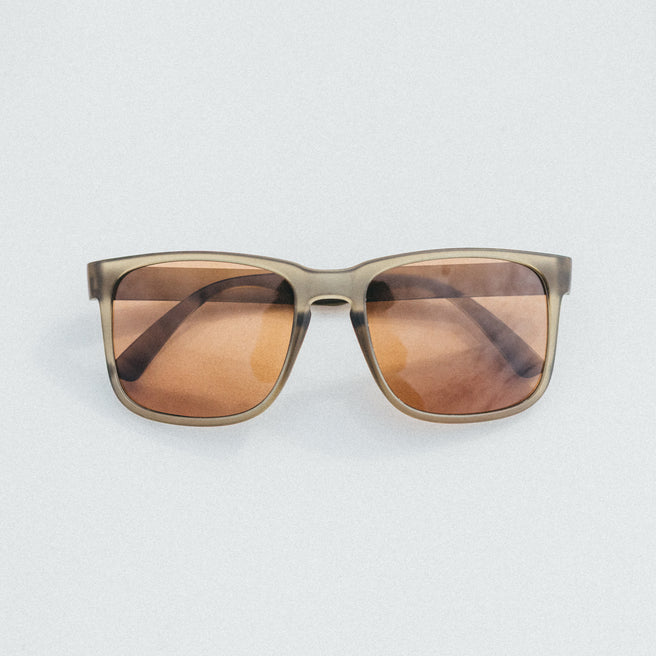 Sunglasses with brown lenses and gold frame on a light gray background