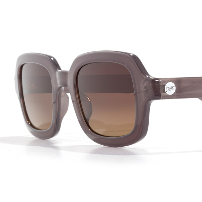 Sunglasses with brown gradient lenses and a clear frame on a white background