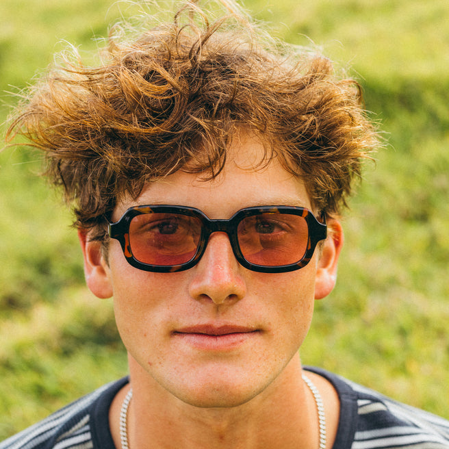 Person wearing sunglasses with a blurred green background