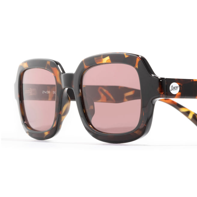 Sunglasses with tortoiseshell frame and pink lenses on a white background