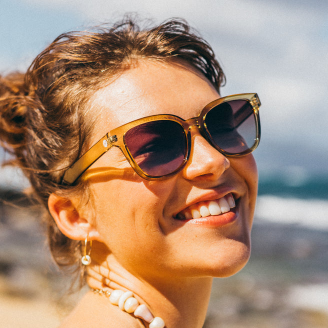 Woman wearing sunglasses with a blurred beach background