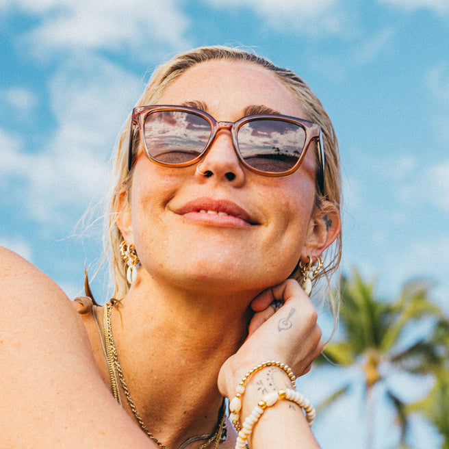 Woman wearing sunglasses with a tropical background