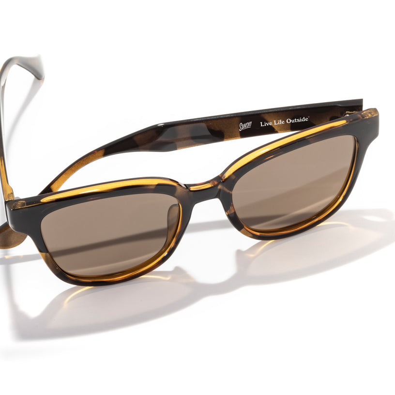 Sunglasses with tortoiseshell frame and brown lenses on a white background