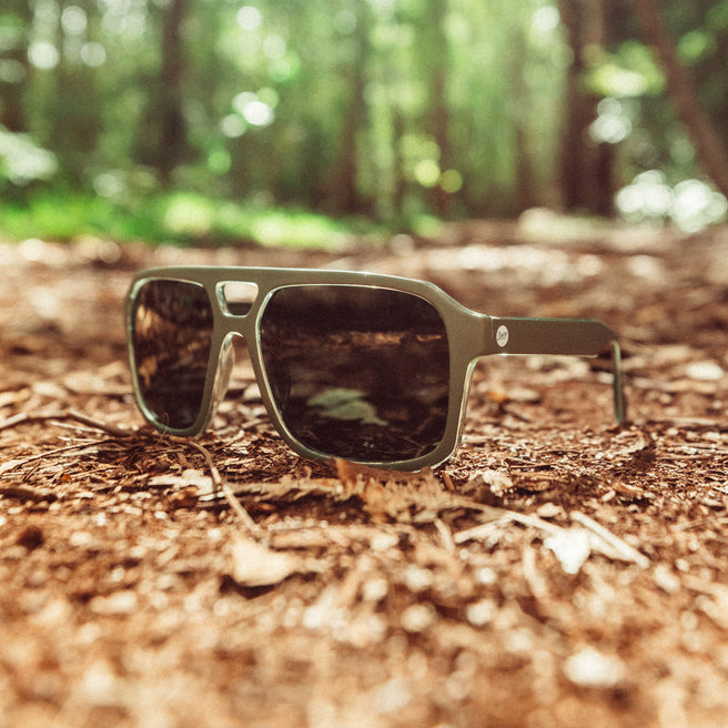 Sunglasses on a forest floor with blurred greenery in the background
