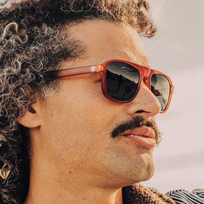 Man wearing red sunglasses with a blurred natural background