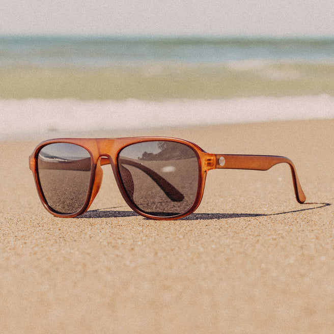 Sunglasses on a sandy beach with ocean in the background