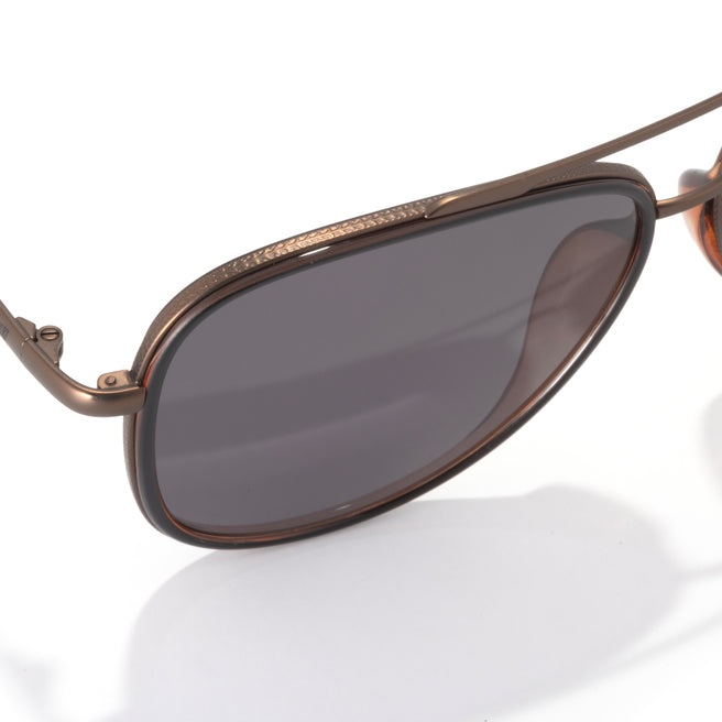 Sunglasses with bronze frame and dark lenses on a white background