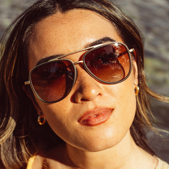 Close-up of a person wearing sunglasses with a blurred natural background