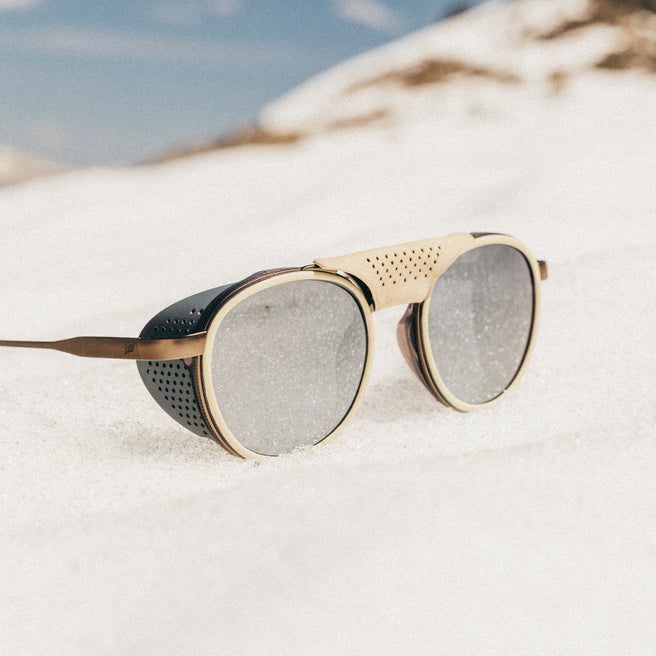 Sunglasses with gold frame and gray lenses on a sandy surface
