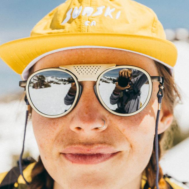 Strada - Ivory Silver - Person wearing a yellow cap and reflective sunglasses with a snowy landscape in the background