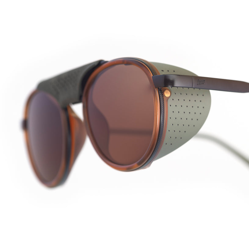 Sunglasses with round lenses and a green frame on a white background