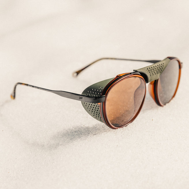Strada - Rust Amber - Sunglasses with brown lenses and black frames on a light beige background