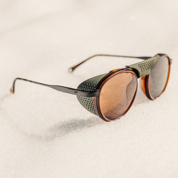 Sunglasses with brown lenses and black frames on a light beige background