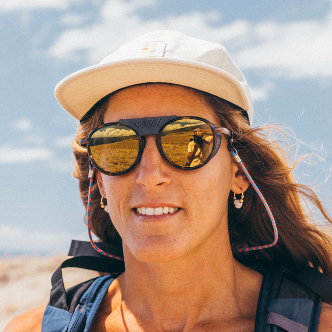 Person wearing sunglasses and a cap with a clear sky background