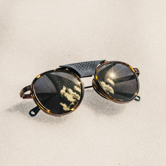 Strada - Tortoise Flash Gold - Round sunglasses with reflective lenses on a sandy background