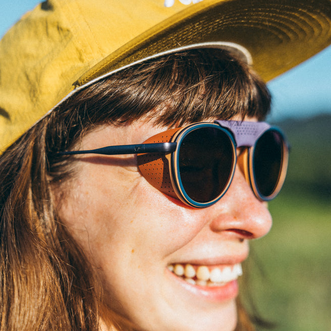 Strada - Violet Galaxy - Person wearing a yellow cap and round sunglasses with a blurred natural background