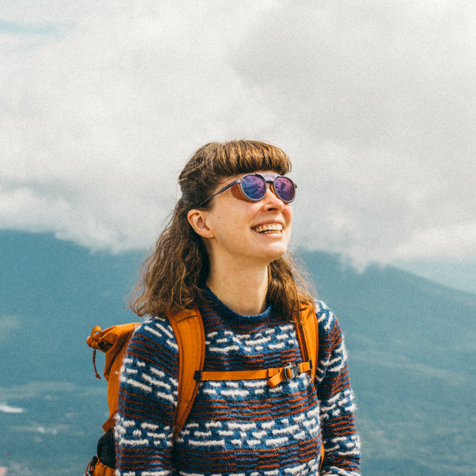 Person with sunglasses and backpack against a mountainous background