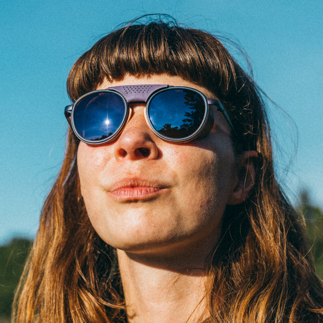 Person wearing reflective sunglasses against a clear blue sky