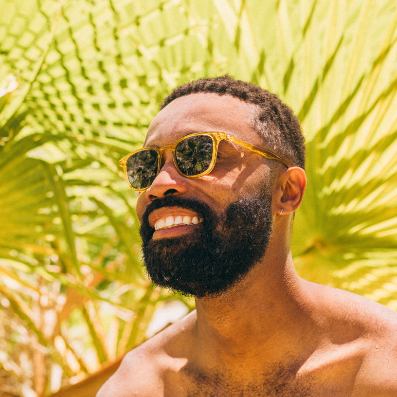 Man wearing sunglasses with a tropical background