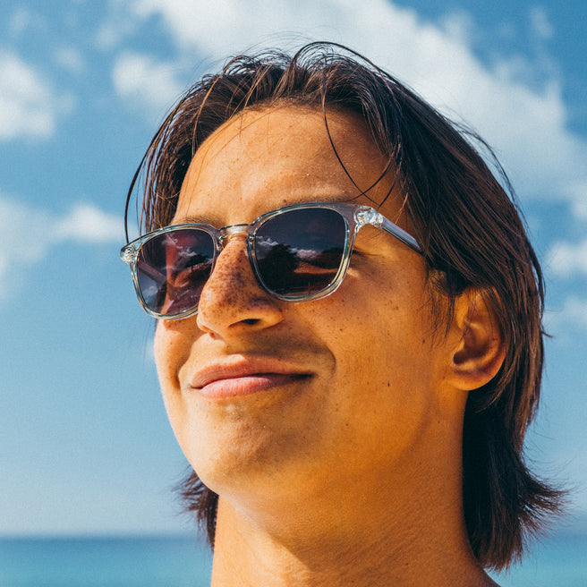Person wearing sunglasses with a blue sky and ocean background