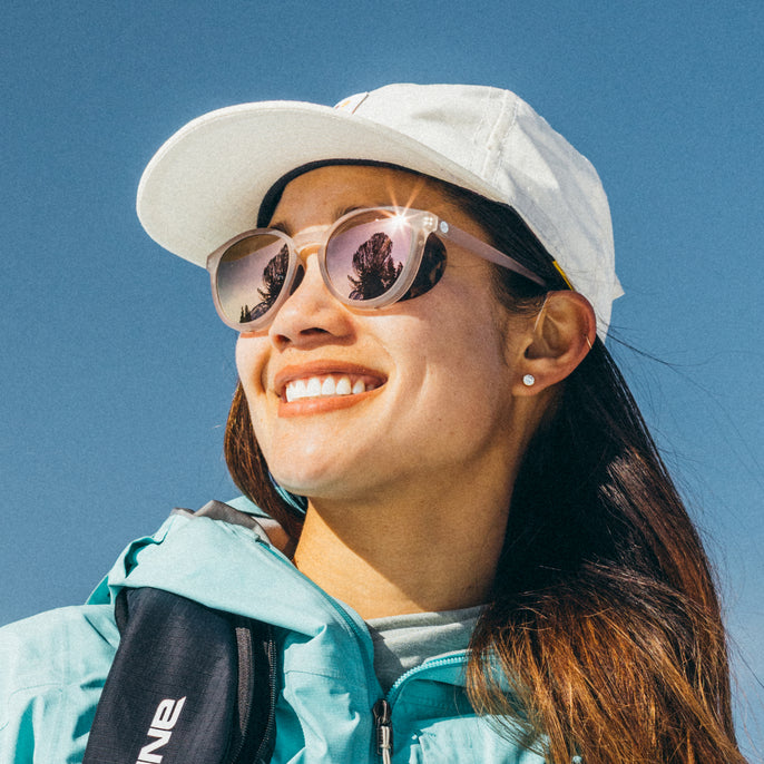 Woman wearing a white cap and sunglasses with a clear blue sky background