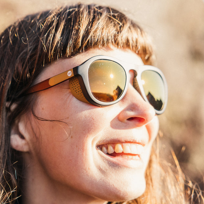 Person wearing reflective sunglasses with a blurred natural background