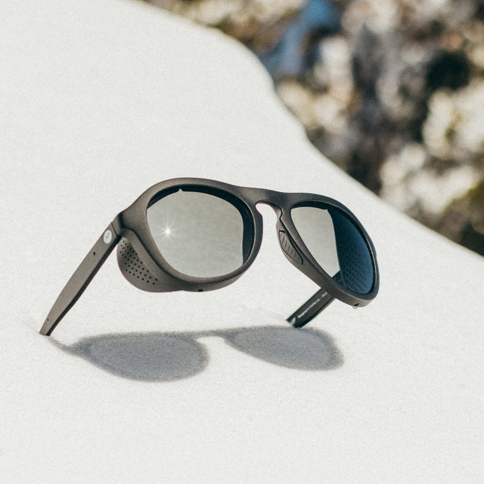 Sunglasses on a white surface with a blurred natural background